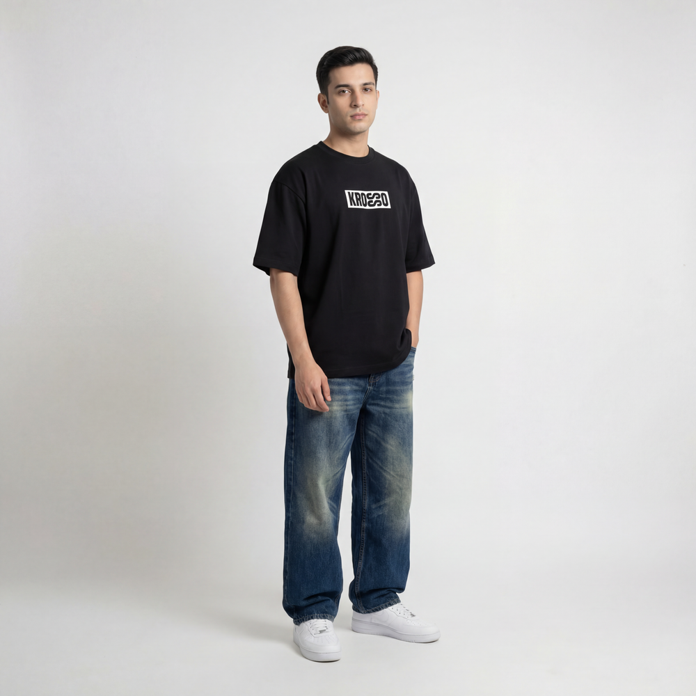 Front view of model wearing Krosso oversized black t-shirt with minimal logo branding and oversized streetwear fit.